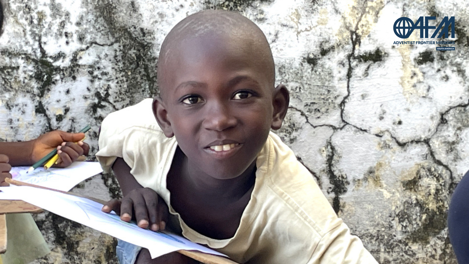 Levi, criança de Guiné Bissau com caderno, sorrindo