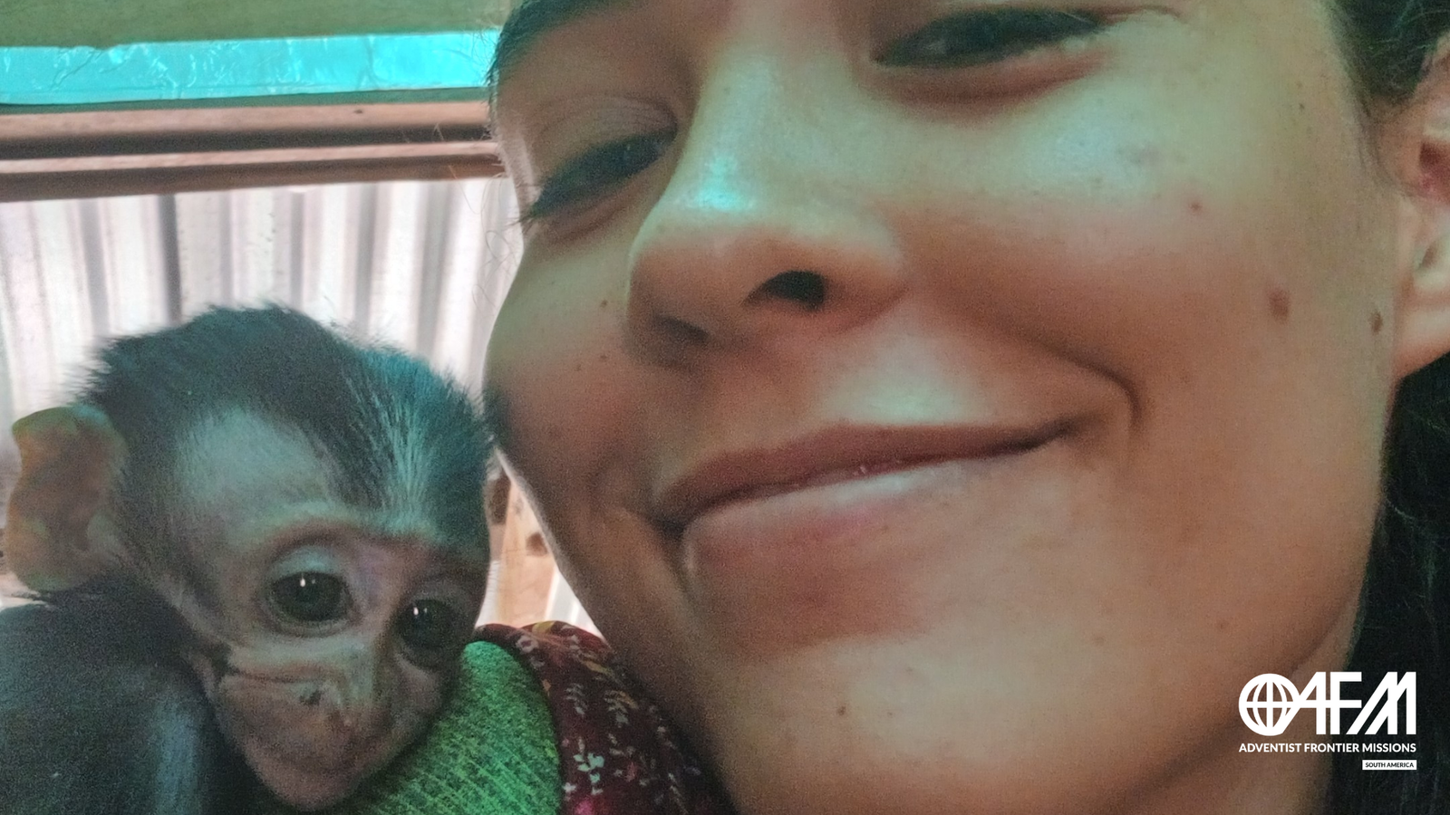 Sentir a presença - Missionária sorrindo enquanto é abraçada por pequeno macaco de olhar triste