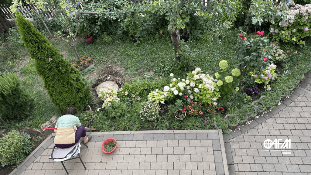 O jardim florido sendo cuidado por uma senhora sentada em uma cadeira