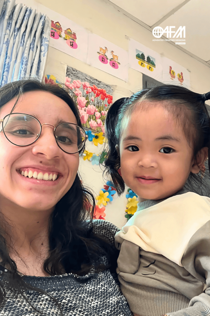 Equador e Camboja, missionária com menina cambojana no colo sorrindo.