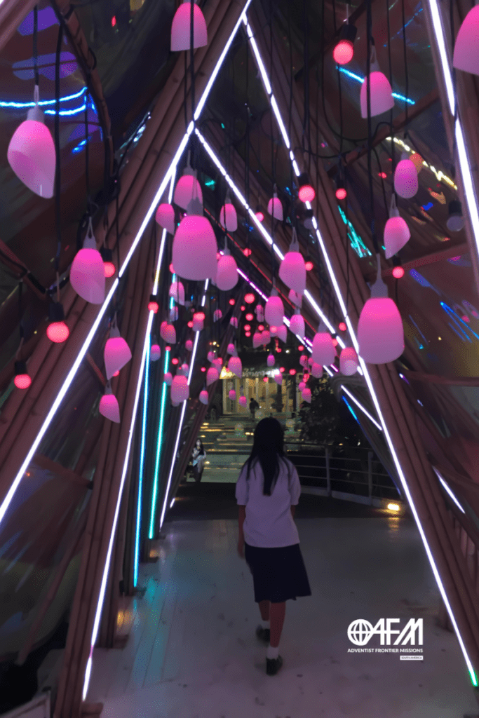 Quando Deus usa o digital para missões: menina Tai Kadai andando por um corredor iluminado.