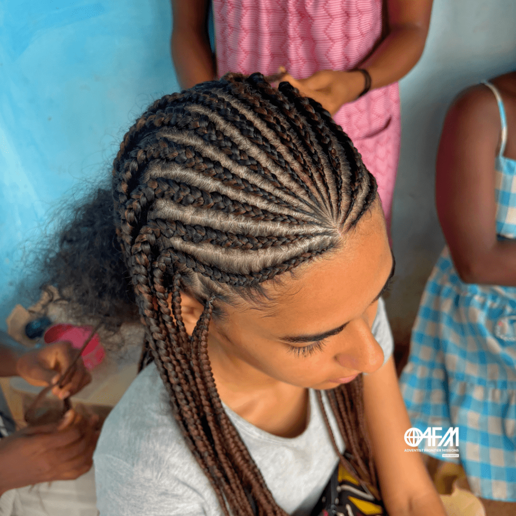 O evangelho não é uma invasão cultural. Missionária tendo o cabelo trançado por uma jovem africana.