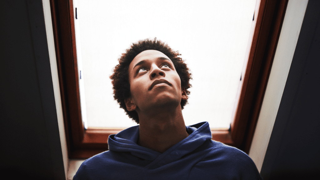 Qual é o propósito de Deus para você - jovem negro olhando reflexivo para o alto